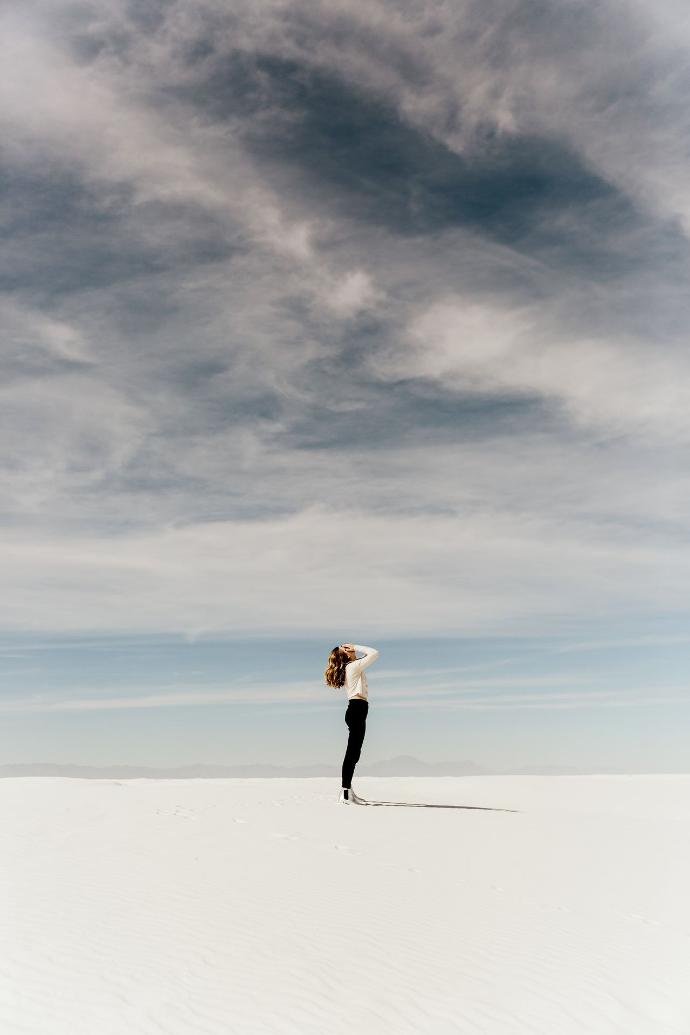 Ervaring Alexadra woman looking up to the sky while standing on white sand